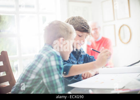 Boys drawing together at table Stock Photo