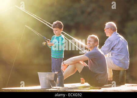 Boy, father and grandfather fishing on wooden dock Stock Photo
