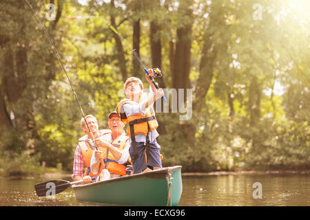 Boy, father and grandfather fishing from canoe on lake Stock Photo