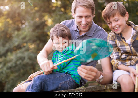 Father and sons fishing with net on dock Stock Photo