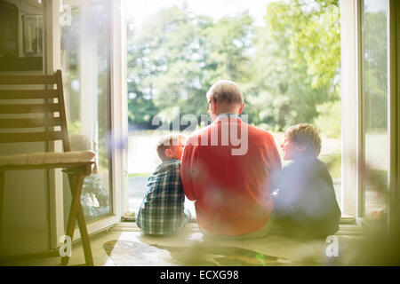 Grandfather and grandsons sitting in doorway Stock Photo