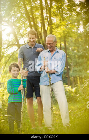 Boy, father and grandfather holding sticks in forest Stock Photo
