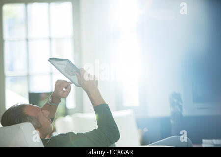 Older man using digital tablet on sofa Stock Photo