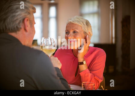 Older couple toasting each other with white wine Stock Photo