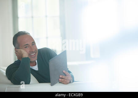 Older man using digital tablet on sofa Stock Photo