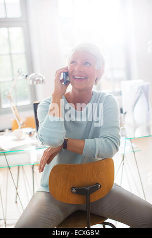 Businesswoman talking on cell phone in office Stock Photo