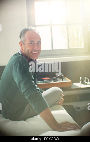 Older man listening to record player with headphones Stock Photo