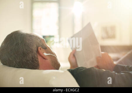 Older man listening to headphones on sofa Stock Photo
