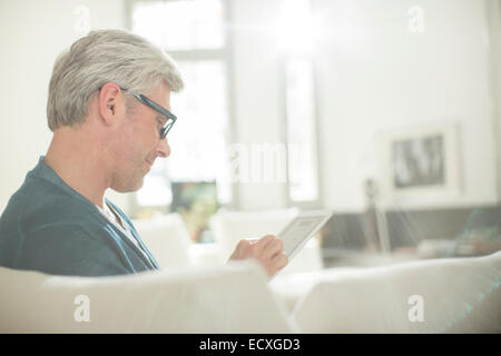 Older man using digital tablet on sofa Stock Photo