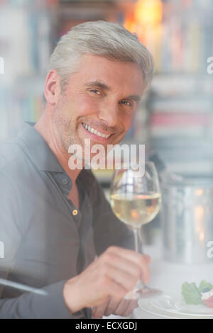 Older man drinking white wine at dinner Stock Photo