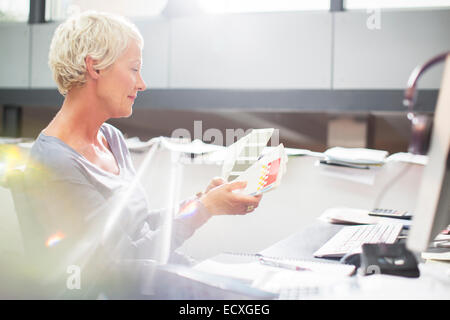 Businesswoman examining paint swatches at office desk Stock Photo