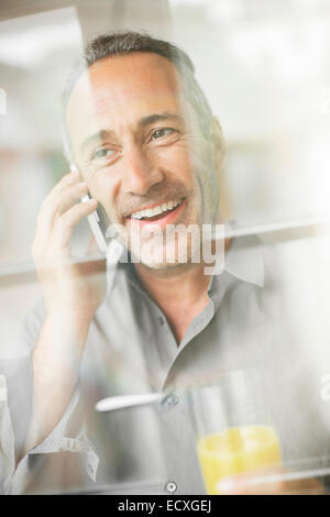 Older man talking on cell phone at breakfast Stock Photo