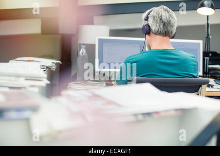 Businessman listening to headphones in office Stock Photo