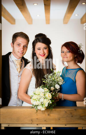 Getting married / Wedding day UK: the happy smiling bride and groom with the bridesmaid posing for photograph Stock Photo