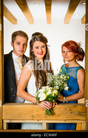 Getting married / Wedding day UK: the happy smiling bride and groom with the bridesmaid posing for photograph Stock Photo