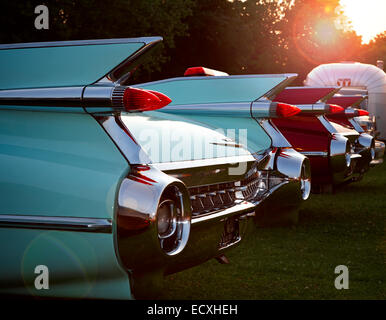 Fins and rear bumpers on two vintage Cadillac Eldorado with American Avion trailer in background with sunburst in sky. Stock Photo