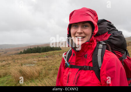 Smiling girl in rain clothing on moors on the slopes of Moel Siabod, Capel Curig, Gwynedd, North Wales, UK Stock Photo
