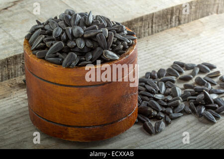 Roasted and salted sunflowers seeds in their shells, in bowl over old wood background Stock Photo