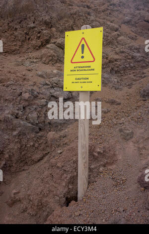 Tourists' warning sign embedded in lava rock at the dormant crater edge of Vesuvius volcano. Stock Photo