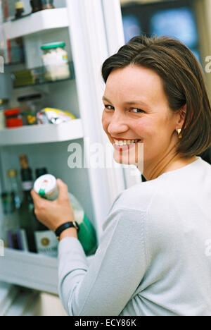 Woman takes a milk bottle from the fridge Stock Photo