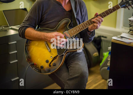 Man playing guitar inside room Stock Photo