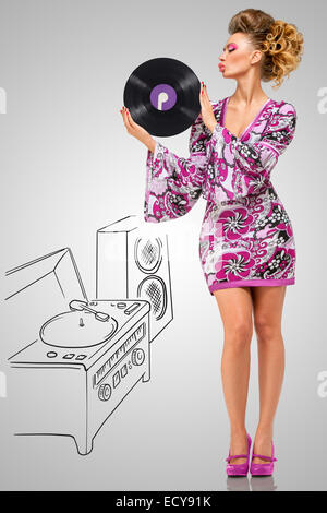Colorful photo of a clubbing fashionable hippie homemaker sending a kiss to a retro vinyl record in her hands on grey sketchy ba Stock Photo