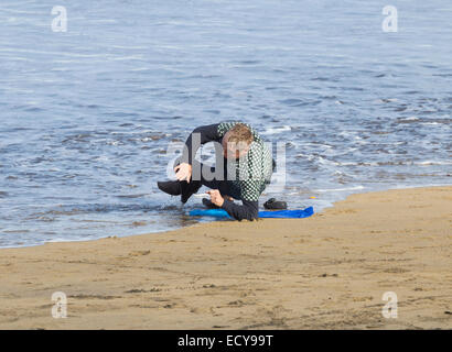 Man snoozing on beach is soaked by the incoming tide. Stock Photo