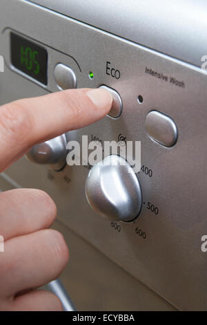 Woman Selecting Economy Program On Washing Machine To Save Energy Stock Photo
