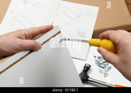 Close Up Of Man Assembling Flat Pack Furniture With Screwdriver Stock Photo