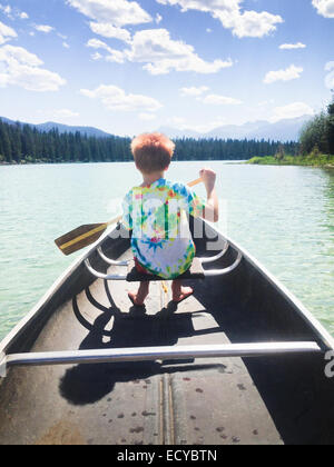 Caucasian boy rowing canoe on still lake Stock Photo