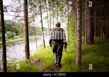 Mari man in wading boots walking near river in forest Stock Photo