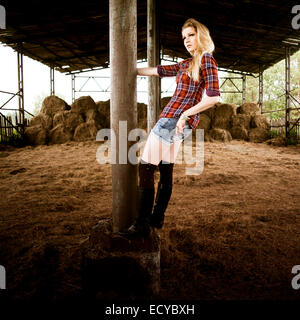 Caucasian woman standing on pole in barn Stock Photo