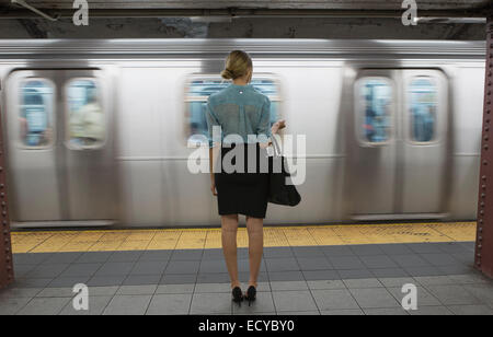 Caucasian woman standing near passing subway in train station