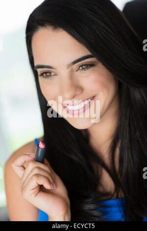 Hispanic woman applying lipstick Stock Photo