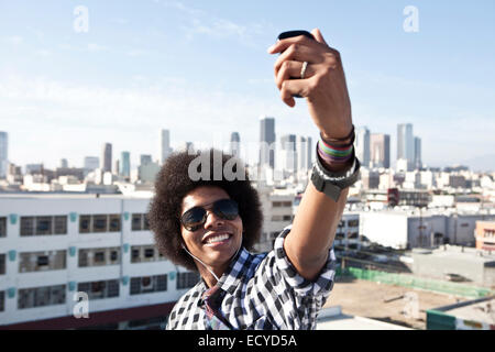 African American man taking cell phone picture from urban rooftop