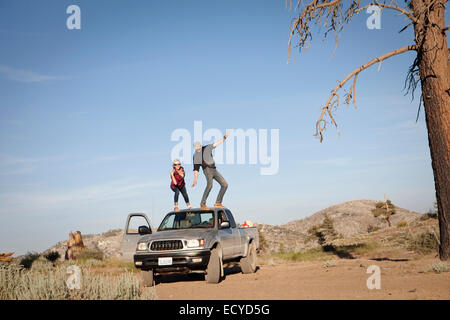 Caucasian couple standing on roof of pickup truck Stock Photo