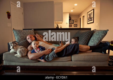 Caucasian father and children relaxing on sofa Stock Photo