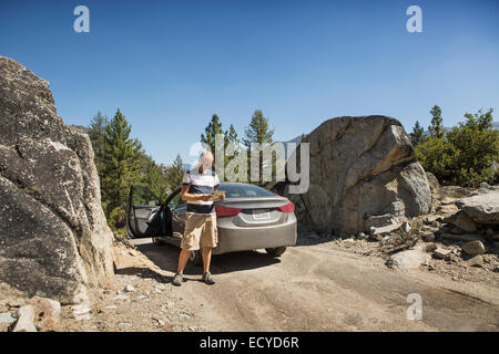 Man reading near car on dirt road Stock Photo