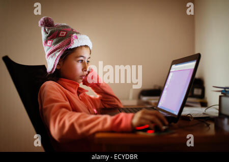 Mixed race girl using laptop at desk Stock Photo