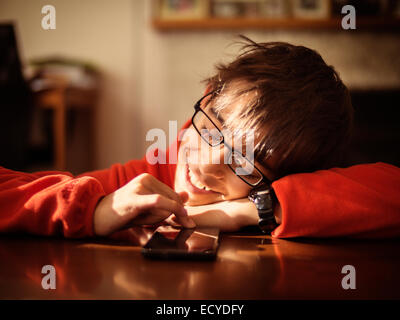 Mixed race boy using cell phone at table Stock Photo