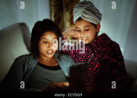 Mixed race mother and daughter using digital tablet at night Stock Photo