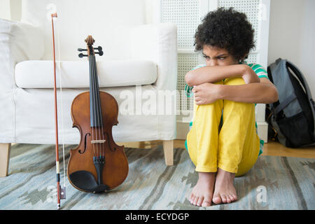 Angry mixed race boy refusing to practice violin Stock Photo