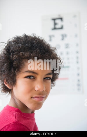 Mixed race boy squinting near eye chart Stock Photo