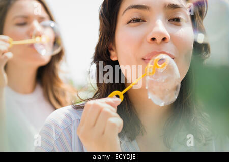 Hispanic women blowing bubbles outdoors Stock Photo