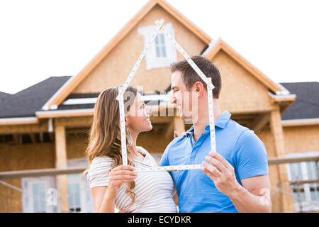 Caucasian couple holding frame near house under construction Stock Photo