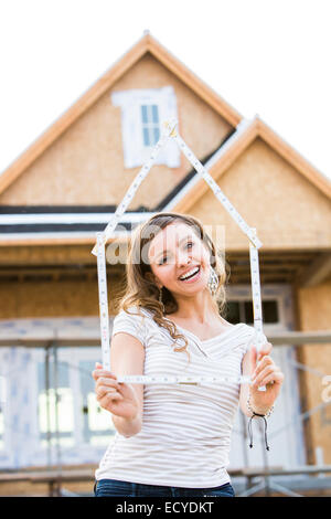 Caucasian woman holding frame near house under construction Stock Photo