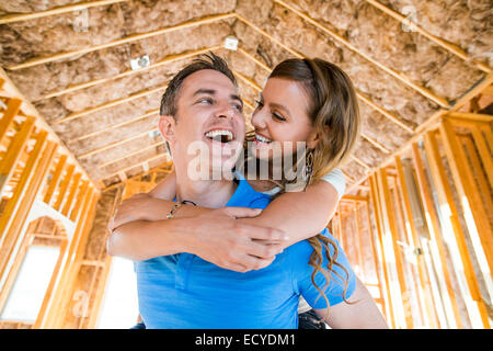 Caucasian couple hugging in house under construction