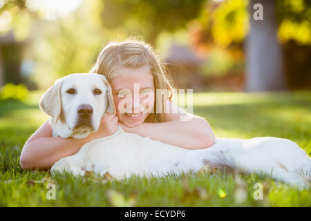 Caucasian girl hugging pet dog on grassy lawn