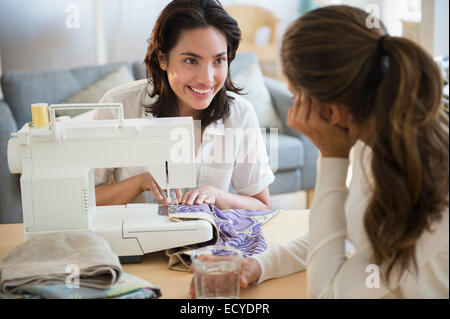 Hispanic women using sewing machine in living room Stock Photo