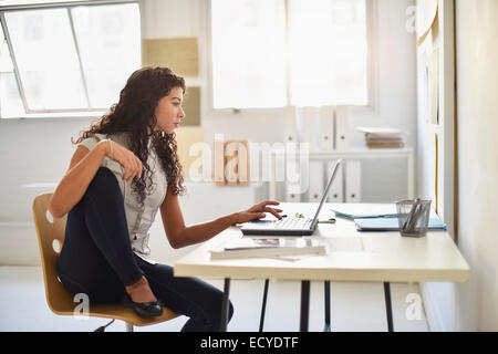 Mixed race businesswoman working on laptop at desk in office Stock Photo